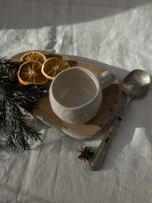 tasse crème vu du haut sur un rondin de bois avec oranges séchées et branches de sapin sur le coté + cuillère.